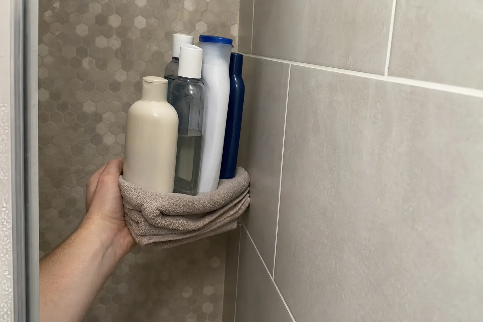 Folded towel and bottles used to test how far a shower caddy would project into a narrow shower